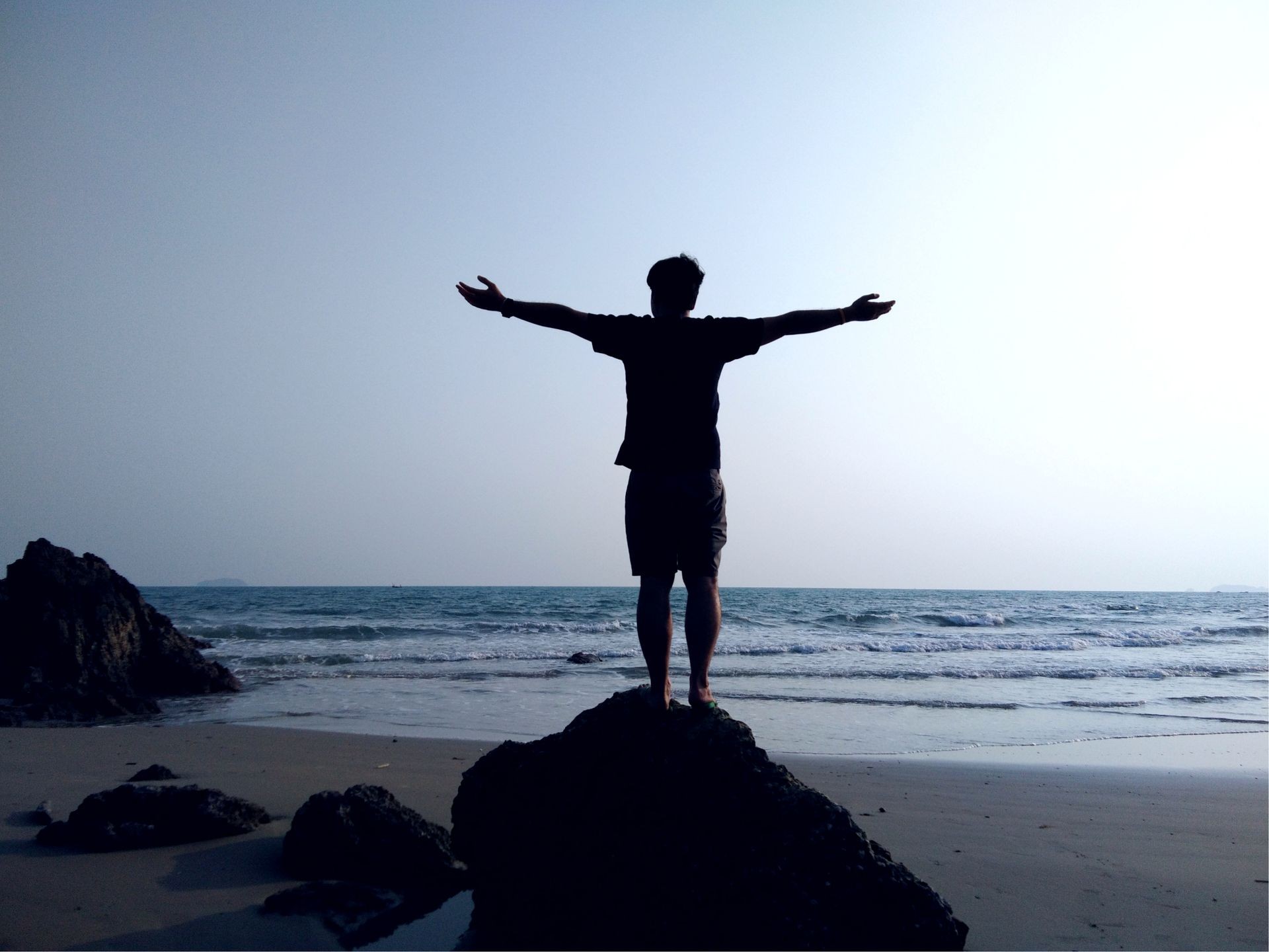 A human standing on the rock in seaside on the beach. Life coaching and success concept
